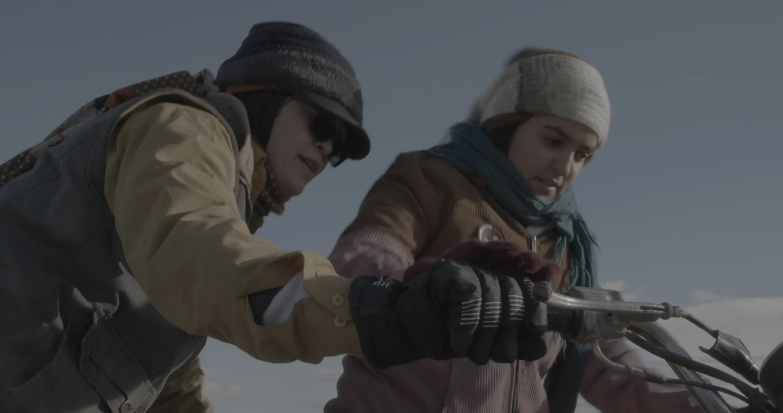 One woman on a bike and one helping her.