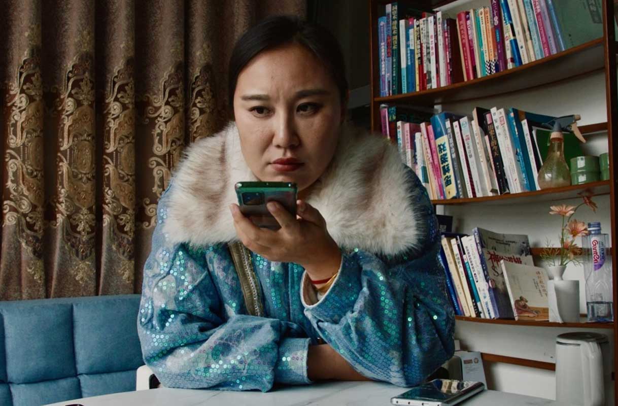 Woman listening to her phone in front of a bookcase