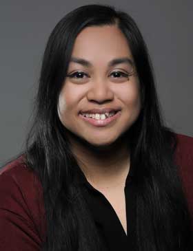 A person with dark hair in front of a dark background.