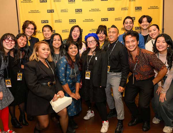 Asian American Documentary Members (A-Doc) strike a pose in front of a step and repeat at the American Documentary (AmDoc) Gala.