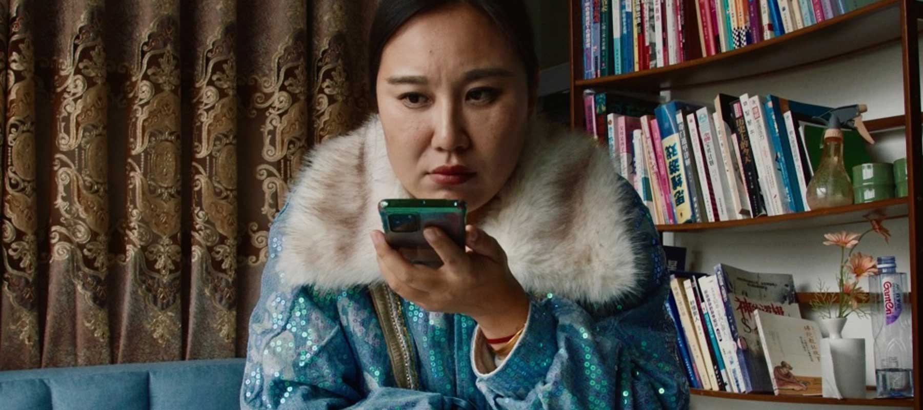 A woman is seated with her phone. 